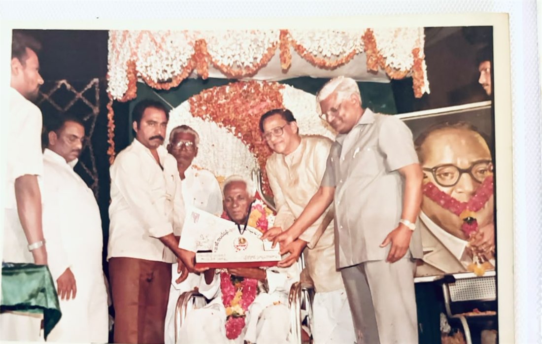 Konada Surya Prakasa Rao being felicitated beside a portrait of Dr. B. R. Ambedkar